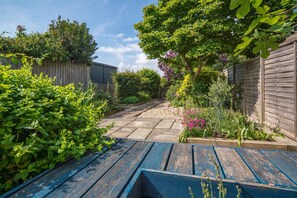 Ein Garten mit Holzzaun, einem Weg und verschiedenen Pflanzen.