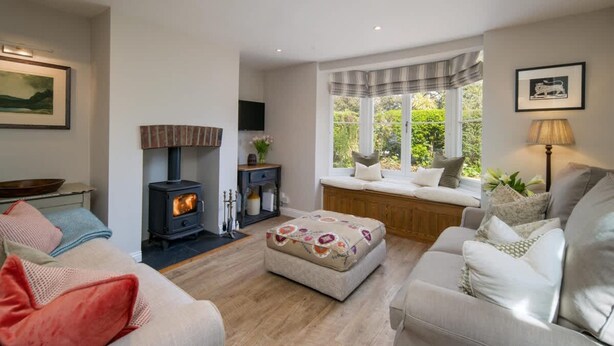 A cozy living room with a fireplace, comfortable seating, and a window with a view. - Lily Cottage Charming Gurnard Retreat by the Sea (Cowes)