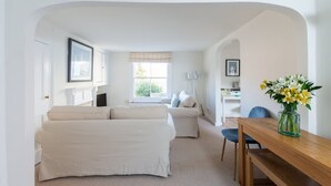 A room with a bed, a sofa, a dining table, and a vase of flowers. - Bars Hill Cottage Moments From the Seafront (Cowes)