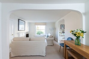 Ein Zimmer mit einem Bett, einer Couch, einem Esstisch und einem Blumenstrauß.