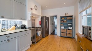 Une cuisine moderne avec des meubles gris, un plancher en bois, un réfrigérateur en acier inoxydable et un four à micro-ondes.