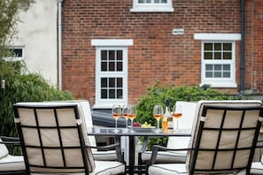 A table set for two with chairs, a glass of wine, a bottle of wine, and a bowl of fruit. - Crossjack Cottage Central Cowes (Cowes)