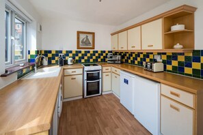 Eine Küche mit Holzarbeitsplatten, einer Mikrowelle, einem Toaster und einem Geschirrspüler.