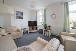A modern living room with a sofa set, a TV, a small table with a plant, and a window with curtains. - The Chambers Apartment Central Cowes (Cowes)