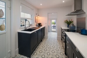 A modern kitchen with a black and white tiled floor, a sink, and a stove. - Wistaria Cottage Beautifully Renovated Cottage (Cowes)