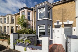 A row of terraced houses with a gated entrance, a small garden, and a brick wall. - Wistaria Cottage Beautifully Renovated Cottage (Cowes)