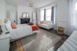Ein Schlafzimmer mit Bett, Sofa, Kamin und einem Fenster mit Vorhängen.