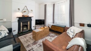Ein Wohnzimmer mit Kamin, Sofa, Fernseher und Couchtisch.