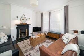 Ein Wohnzimmer mit Kamin, Sofa, Fernseher und Couchtisch.