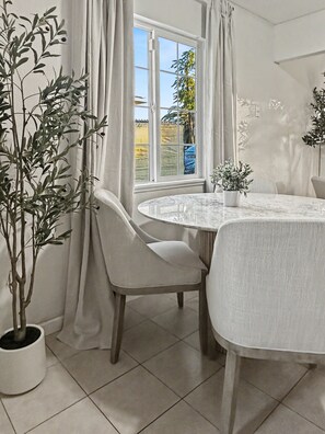 A room with a round table, two chairs, a potted plant, and a window with curtains. - Central Fremont. Convenient to all shops and downtown. Delux comfy. (Fremont)