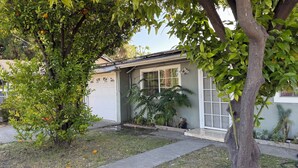 Ein Wohnhaus mit Garage, Rasen und verschiedenen Pflanzen.