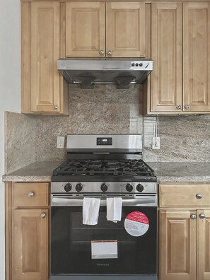 A kitchen with wooden cabinets, a stainless steel stove, and a granite countertop.