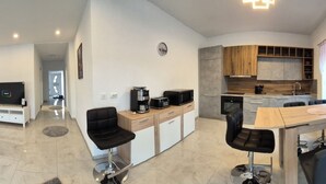 Una sala de estar moderna con un sofá, un televisor y una cocina con una mesa de comedor y sillas.