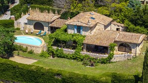 Eine Steinvilla mit Swimmingpool, Sitzgelegenheiten im Freien und üppigem Grün.