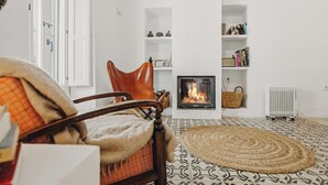 Una sala de estar con chimenea, un sofá y un tapete estampado.
