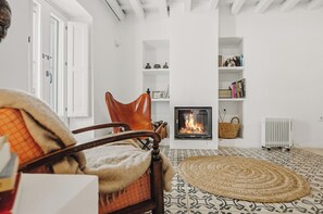 A living room with a fireplace, a sofa, and a patterned rug. - Beautiful house in the historic center of Vejer de la Frontera (Vejer de la Frontera)