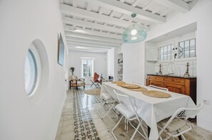 A dining area with a white table, chairs, and a patterned floor. - Beautiful house in the historic center of Vejer de la Frontera (Vejer de la Frontera)