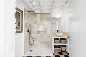 A modern bathroom with a shower, sink, and tiled walls. - Beautiful house in the historic center of Vejer de la Frontera (Vejer de la Frontera)