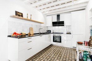 A modern kitchen with white cabinetry, a black countertop, and a patterned floor. - Beautiful house in the historic center of Vejer de la Frontera (Vejer de la Frontera)