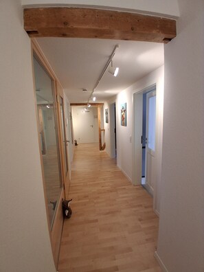 A hallway with wooden flooring, white walls, and a wooden beam ceiling. - Höflepanorama Apartment: Sauna, Fireplace, Grill, View, Balcony, Groups, Wi-Fi (Oppenau)