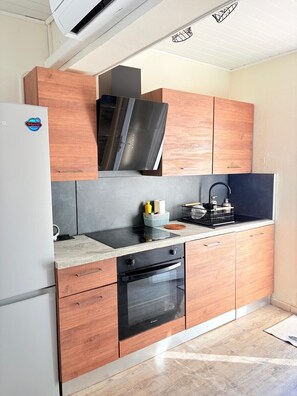 Eine moderne Küche mit Holzausstattung, einem eingebauten Ofen und einer Edelstahl-Dunstabzugshaube.