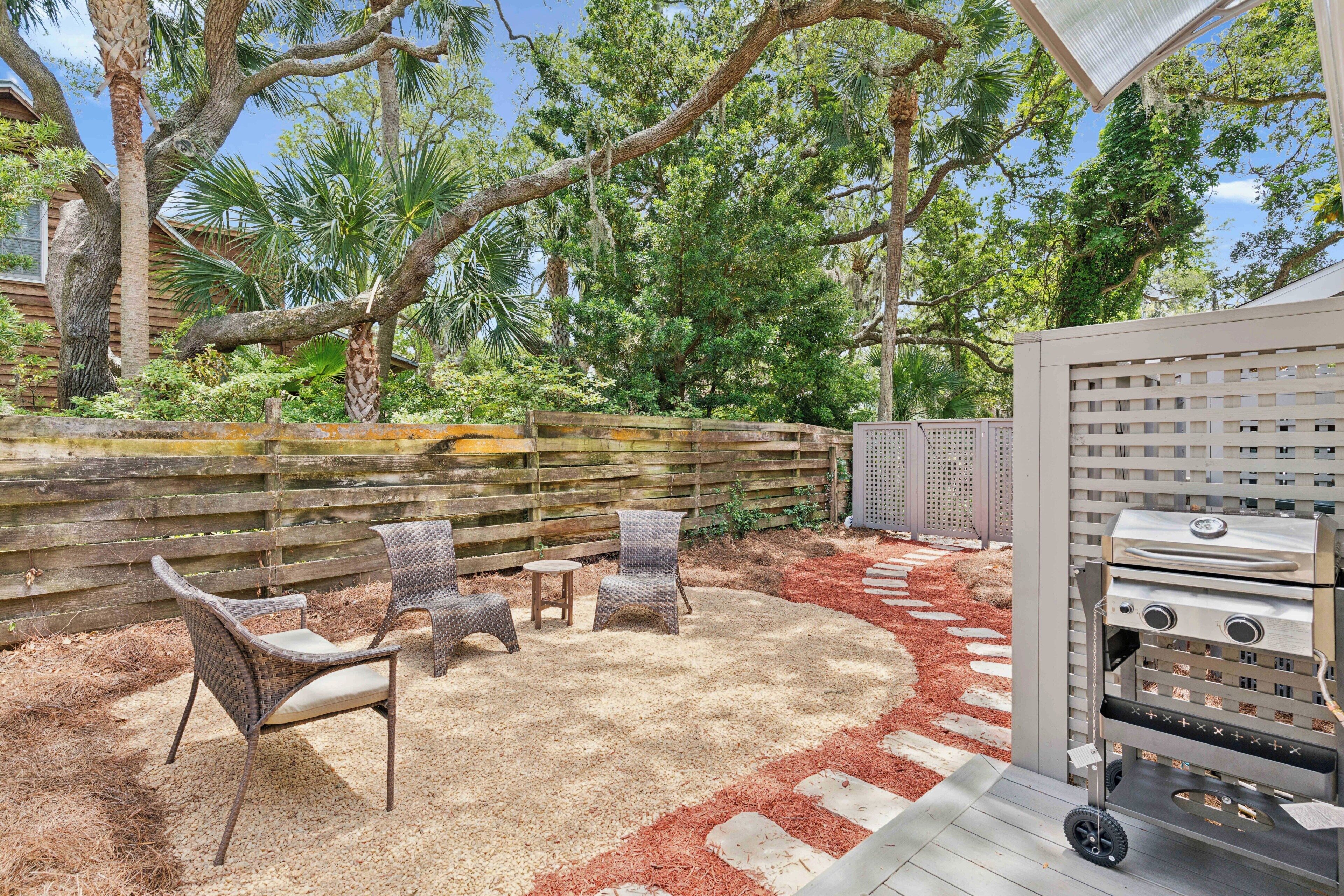 A patio with wicker furniture, a grill, and a wooden deck.