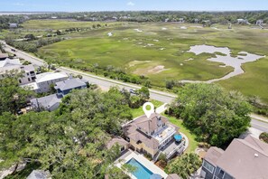 A residential area with houses, a swimming pool, and a large green field with water bodies. - Upscale East Beach & Pool (St Simons Island)