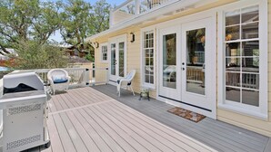 Une terrasse en bois avec des sièges d’extérieur, un barbecue et un espace abrité doté d’une rambarde.