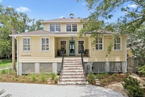 A two-story house with a front porch, a green door, and a staircase leading to the entrance. - Upscale East Beach & Pool (St Simons Island)