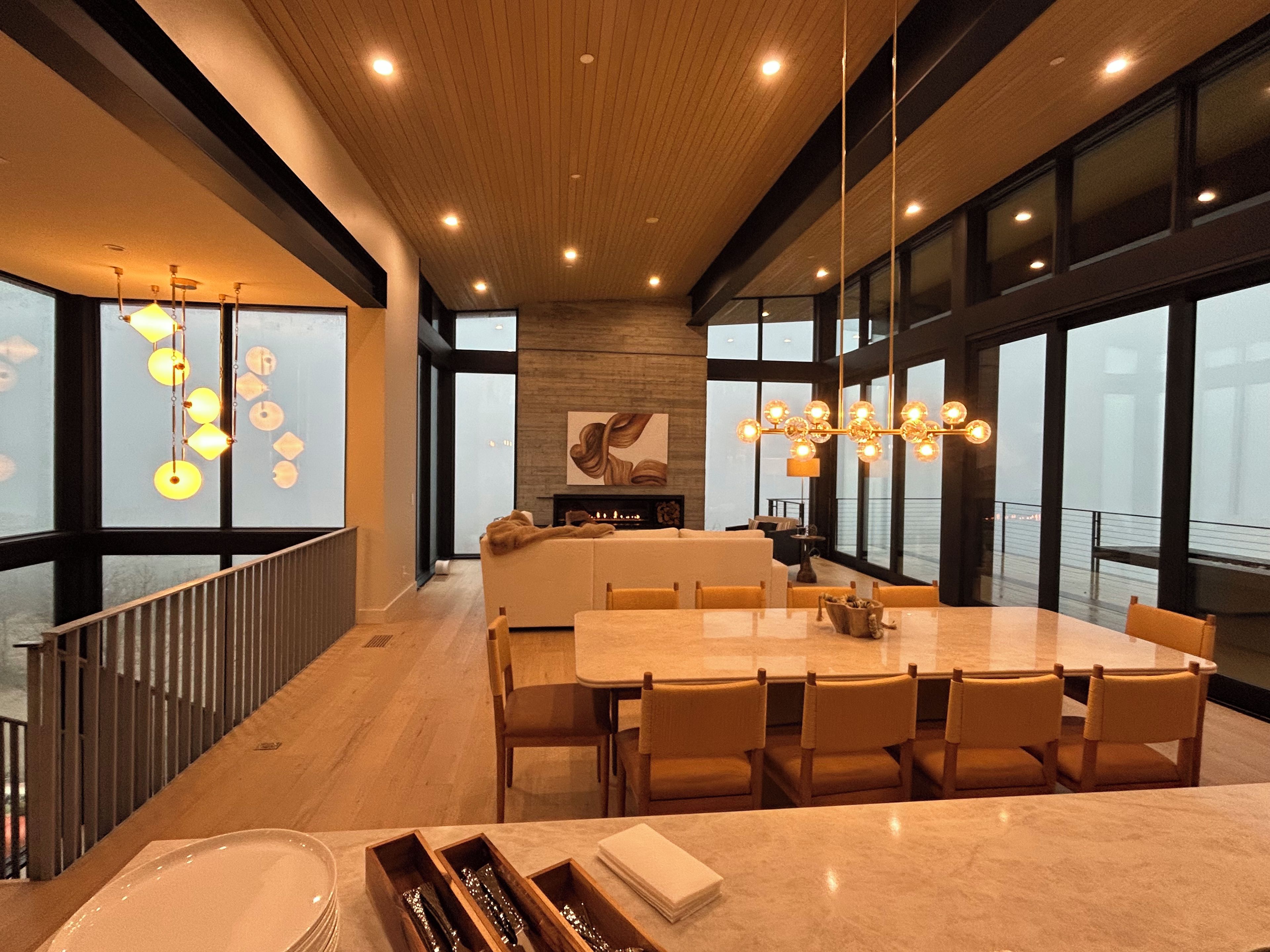 A modern interior with a dining area, large windows, and a staircase. - Ski in/ski out whole house rental-Powder Mountain, views, hot tub, sauna & more! (Eden)