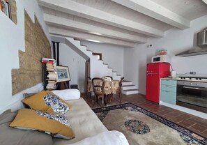 Ein Wohnzimmer mit einer Couch, einem Esstisch mit Stühlen, einer Treppe, einem roten Kühlschrank und einem Herd.