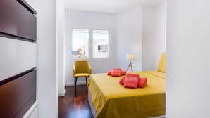Ein Schlafzimmer mit einem Bett, einem Sessel, einer Lampe und einem Fenster.