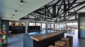 Una cucina moderna con isola centrale, sgabelli da bar e un soffitto alto con travi a vista.
