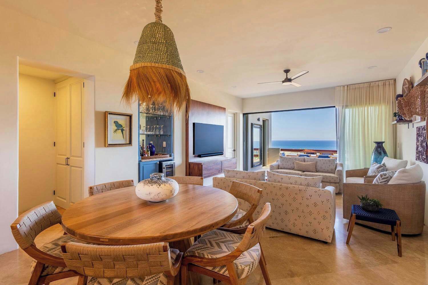 Ein modernes Wohnzimmer mit Essbereich, Fernseher und Meerblick.
