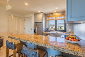 A kitchen with granite countertops, stainless steel appliances, and a view of a cityscape. - 3BR Ocean and City View - Pool - Tennis (San José del Cabo)