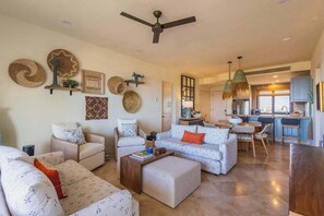A spacious living area with a ceiling fan, multiple seating options, and a kitchen in the background. - 3BR Ocean and City View - Pool - Tennis (San José del Cabo)