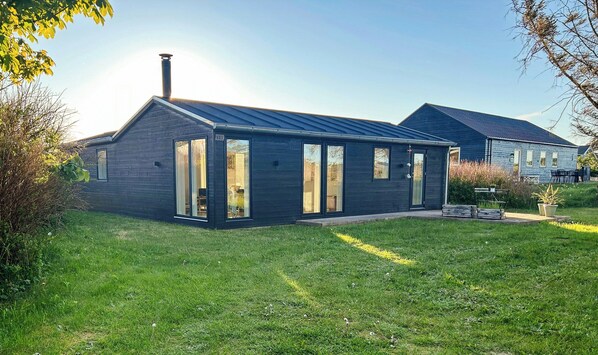 Ein modernes Haus mit Satteldach, großen Fenstern und Schornstein.