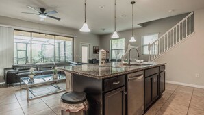A modern kitchen with a central island, stainless steel appliances, and pendant lighting. - 5BR Solterra Home with Private Pool Near Disney (Davenport)