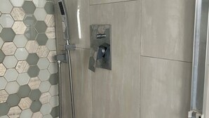 Eine Dusche mit Handbrause und einer fest installierten Bedienfeld.