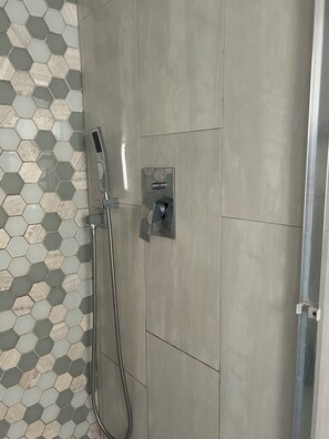 Eine Dusche mit Handbrause und einer fest installierten Bedienfeld.