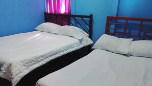 Dos camas individuales con cabeceros de madera y ropa de cama blanca en una habitación con paredes azules.