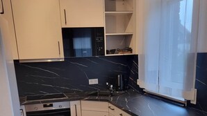 Eine moderne Küche mit weißen Schränken, einer schwarzen Marmorarbeitsplatte und einem eingebauten Backofen.