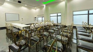A conference room with a long table and rows of chairs, equipped with a projector and a ceiling light fixture. - Kamojama Villa (Abakaliki)