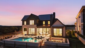 A large house with a swimming pool, outdoor seating, and a well-lit patio area. - Cliffside at the Gate: Lakefront, pool and Basketball/Pickleball Court (Graford)