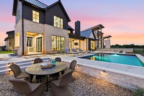 A modern house with a swimming pool, outdoor seating, and a stone facade. - Cliffside at the Gate: Lakefront, pool and Basketball/Pickleball Court (Graford)