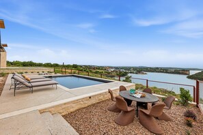 A poolside area with lounge chairs, a dining table, and a view of a lake. - Cliffside at the Gate: Lakefront, pool and Basketball/Pickleball Court (Graford)