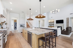 A spacious kitchen with a central island, wooden cabinets, and pendant lighting.