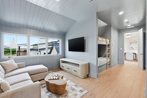 A modern living room with a sofa, TV, and bunk beds. - Cliffside at the Gate: Lakefront, pool and Basketball/Pickleball Court (Graford)