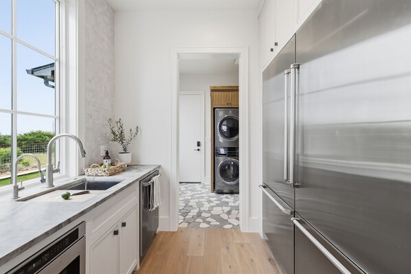 Een moderne keuken met een roestvrijstalen koelkast, een ingebouwde wasmachine en een groot raam.