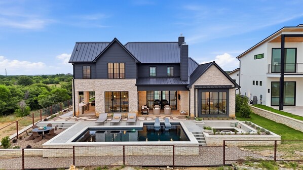 A modern two-story house with a stone facade, a pool, and a patio with outdoor furniture. - Cliffside at the Gate: Lakefront, pool and Basketball/Pickleball Court (Graford)